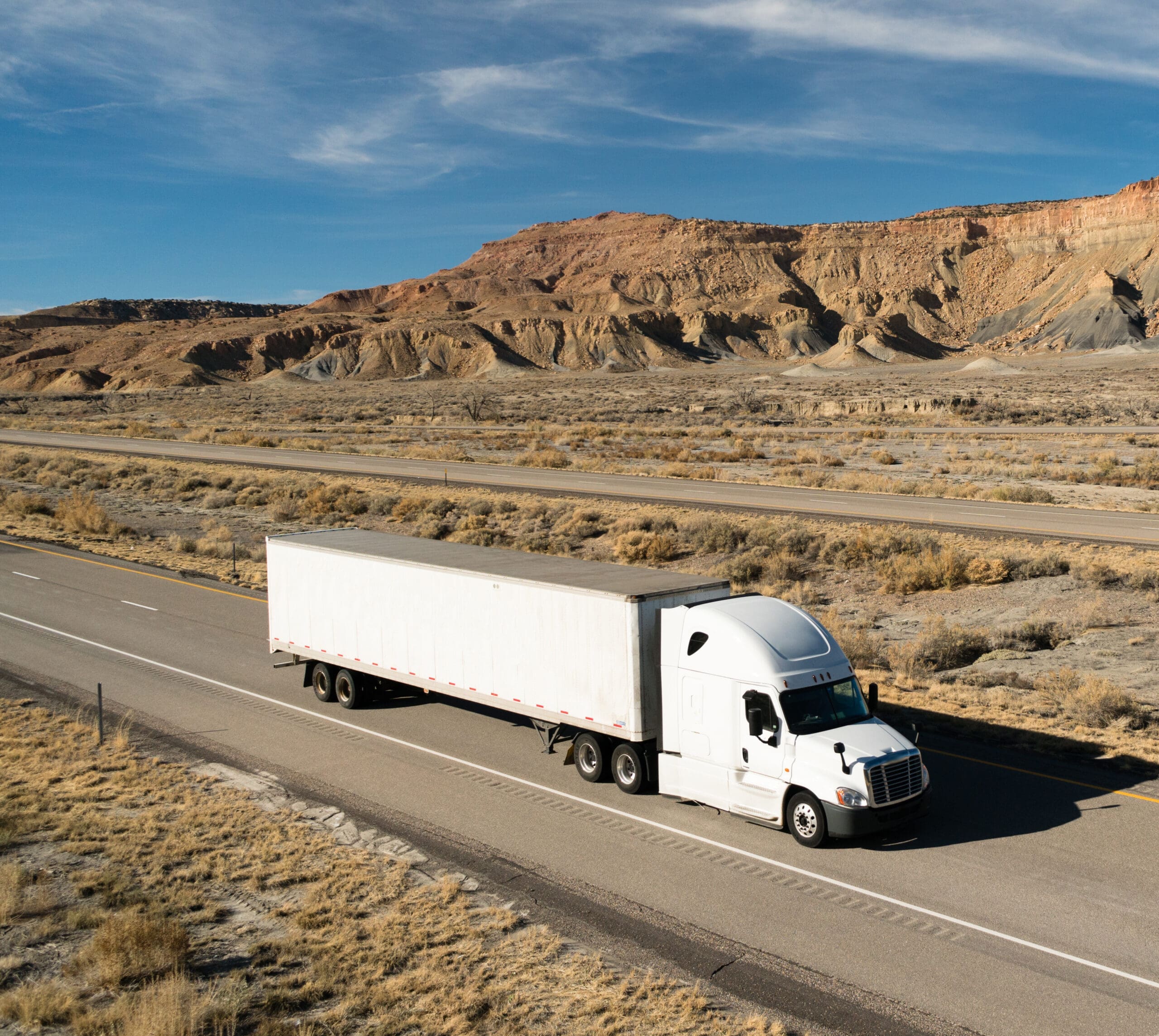 A white big rig rolls across Utah on a devided highway